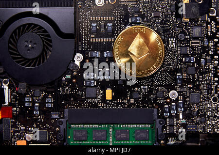 An Ethereum coin sitting on a computer motherboard with a fan and RAM. Ethereum is used for open-source Smart Contracts. Stock Photo