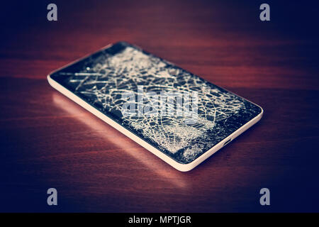 Top view cracked glass screen black and white, close up. Phone repair concept. Old broken phone with black screen. The display cracked in the form of  Stock Photo