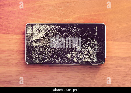 Smartphone mobile with a broken screen. Background wood Stock Photo