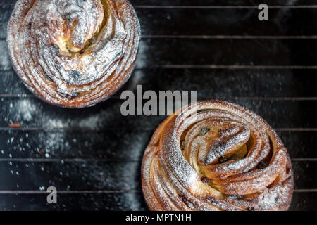 Cupcake pie crunch in the form of a roll sprinkled with powdered sugar on a dark background and an antique grille. Easter and Christmas baking. Top vi Stock Photo