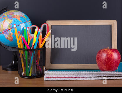 School accessories on a wooden desktop with a blank chalkboard for copy space Stock Photo
