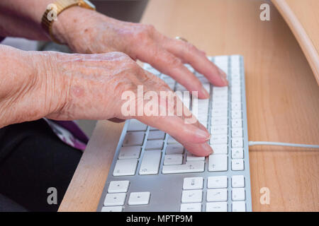 Close-up of a 95-year-old woman's old hands typing on a computer keyboard Stock Photo