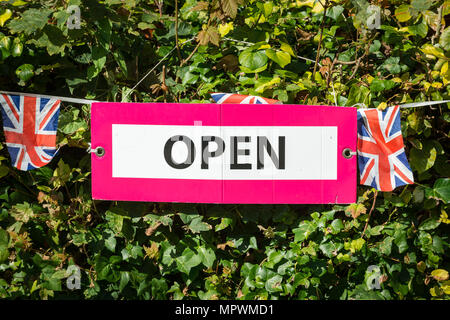 Union jack bunting and a open sign hanging on a hedge. Stock Photo
