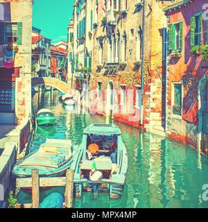 Narrow side canal with moored motorboats in Venice, Italy. Vintage style toned Stock Photo