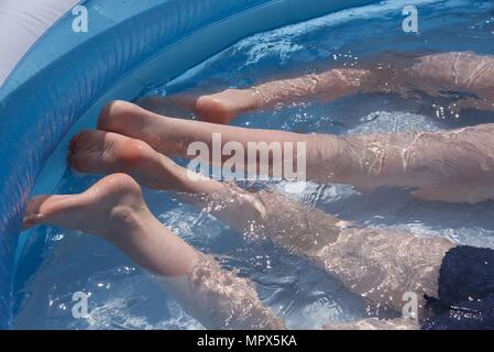 Inflatable paddling pool: two unidentifiable boys playing in an inflatable paddling pool Stock Photo