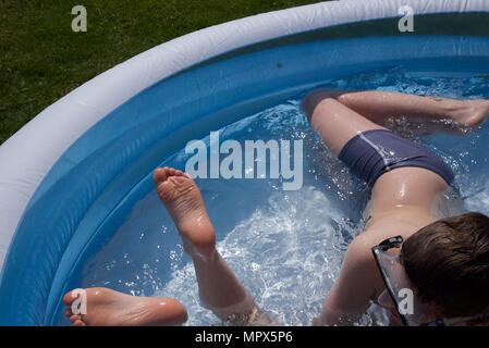 Inflatable paddling pool: two unidentifiable boys playing in an inflatable paddling pool Stock Photo