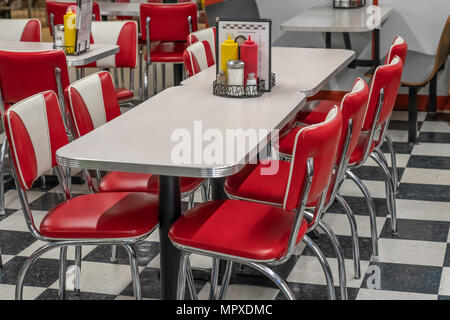 50s style diner with black and white tile floor, red vinyl chairs, and laminate and chrome tables Stock Photo