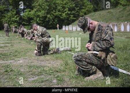 U.S. Marine Lance Cpl. Mitchell R. Neimann, heavy equipment operator with Engineer Company C, 6th Engineer Support Battalion, 4th Marine Logistics Group, loads his ammunition into a magazine on the pistol range firing line next to integrated Marines with 6th ESB and British commando's with 131 Commando Squadron Royal Engineers, British Army, during exercise Red Dagger at Fort Indiantown Gap, Pa. May 15, 2018, May 15, 2018. Exercise Red Dagger is a bilateral training exercise that gives Marines an opportunity to exchange tactics, techniques and procedures as well as build working relationships  Stock Photo