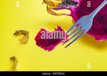 Close-up of bitten pitaya fruit on fork on yellow background Stock Photo