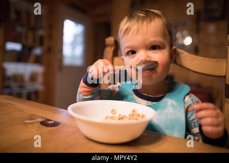 Portrait of cute baby boy eating breakfast while sitting at home Stock Photo