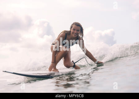 Portrait of carefree smiling woman surfing in sea Stock Photo