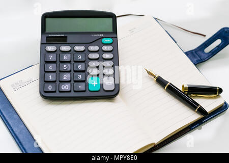 pen, calculator and notebook on the white table backgrounds Stock Photo