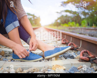 Closeup woman tying shoe laces on the railway platform.  Travel and vacation concept. Stock Photo
