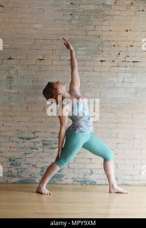 Woman dancing on hardwood floor by wall in studio Stock Photo
