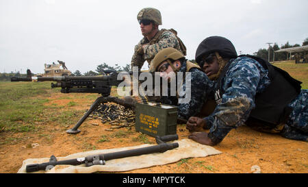 U.S. Marine Corps Cpl. Triston Morrison-Price, left, a machine gunner, initially assigned to Combined Anti-Armor Team 2 Platoon, Weapons Company, 3rd battalion, 8th Marine Regiment, 2nd Marine Division currently forward deployed to 4th Marine Regiment, 3d Marine Division, with MASN Michael Casol and MASN Toderick Jowers assigned to Command Expeditionary Strike Group 7 shoot the M240B machine gun on Range 2, Camp Hansen, Okinawa, Japan, April 12, 2017. Marines instructed Sailors on the M240B medium machine gun and M2 Browning .50 Caliber heavy machine gun to enhance joint force proficiency in c Stock Photo