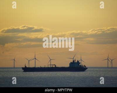 Out Newton wind farm off the Holderness coast viewed from cargo ship entering the Humber Estuary as the sun sets over Holderness Stock Photo