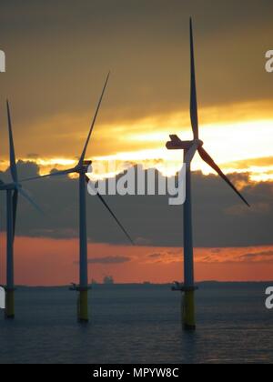 Out Newton wind farm off the Holderness coast viewed from cargo ship entering the Humber Estuary as the sun sets over Holderness Stock Photo