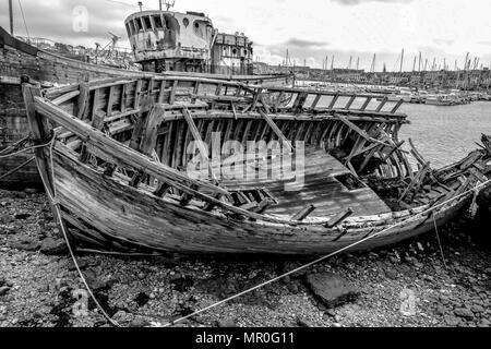 Crumbling ships in the boat graveyard at Camaret-sur-Mer in the Finistere region of Brittany, France. Black and white. B&W Stock Photo