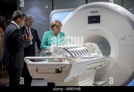 Shenzhen, China. 25 May 2018, China, Shenzhen: German Chancellor Angela Merkel of the Christian Democratic Union (CDU) takes a tour of the company Siemens Shenzhen Magnetic Resonance LTD, alongside Siemens CEO Joe Kaeser (c). The company's general manager Pan Huaiyu (l) shows his visitors an MRI scanner. Merkel is in China for a two-day state visit. Photo: Michael Kappeler/dpa Credit: dpa picture alliance/Alamy Live News Stock Photo