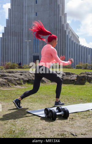Reykjavík, Iceland. 25/05/2018 Weather. Sunny afternoon in the capital as Hannah Eden (Eden Fitness online training) performs a routine for an exercise video, in front of the Hallgrímskirkja church which is Reykjavik’s main landmark. Stock Photo