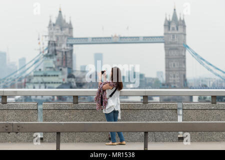 London, UK. 25th May 2018. A tourist takes a photo from London Bridge with Tower Bridge in background. Credit: Guy Corbishley/Alamy Live News Stock Photo