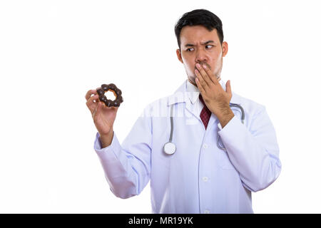 Studio shot of young Asian man doctor holding donut while lookin Stock Photo