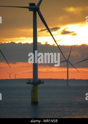 Out Newton wind farm off the Holderness coast viewed from cargo ship entering the Humber Estuary as the sun sets over Holderness Stock Photo