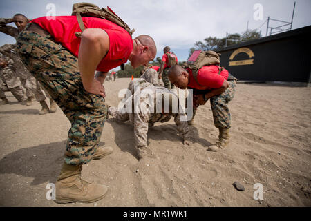 U.S. Marine Corps Sgt. Zachary O’Connor, left, and Staff Sgt. Micah S. Paguia, drill instructors with Company B, 1st Recruit Training Battalion, Recruit Training Regiment, instruct a recruit at Marine Corps Recruit Depot San Diego, Calif., April 6, 2017. O’Connor and Paguia ensured the recruit performed the exercise correctly as he participated in the dynamic warm-up portion of the event. (U.S. Marine Corps photo by Lance Cpl. Erick J. ClarosVillalta) Stock Photo