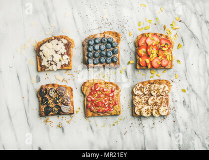 Vegan whole grain toasts with fruit, seeds, nuts, peanut butter Stock Photo