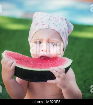 Beautiful sweet girl in a kerchief eats watermelon. Stock Photo
