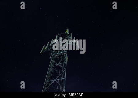 looking up at a communications tower at night with stars Stock Photo