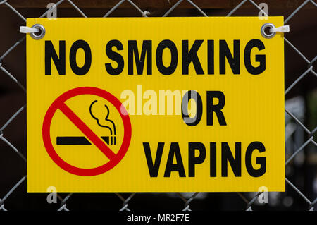 yellow no smoking or vaping sign fastened to a chain-link fence Stock Photo