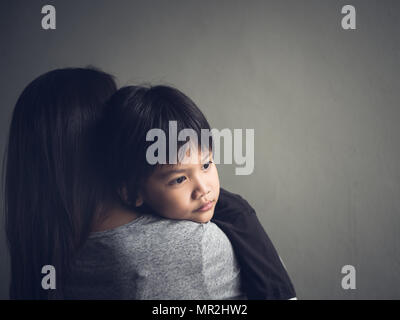 Closeup sad little boy being hugged by his mother at home. Parenthood, Love and togetherness concept. Stock Photo