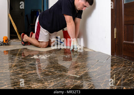 Man placing ceramic floor tile in position over adhesive 2018 Stock Photo
