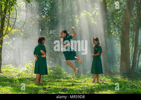 Sakonnakhon, Thailand - July 31, 2016: Three girls in school uniform playing jumping game together on field in rural of Sakonnakhon, Thailand Stock Photo