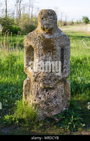 Historical Scythian monuments called kurgan stelae standing in nature against bright green grass, blue sky with clouds Stock Photo