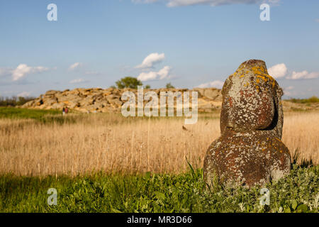 Historical Scythian monuments called kurgan stelae standing in nature against bright green grass, blue sky with clouds Stock Photo