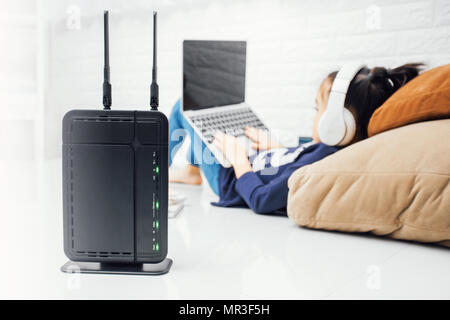 Wireless router and kids using a laptop in home. router wireless broadband home laptop computer phone wifi concept Stock Photo