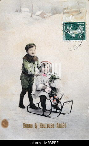 French Happy New Year, postcard depicting two small children with a sledge circa 1900 Stock Photo