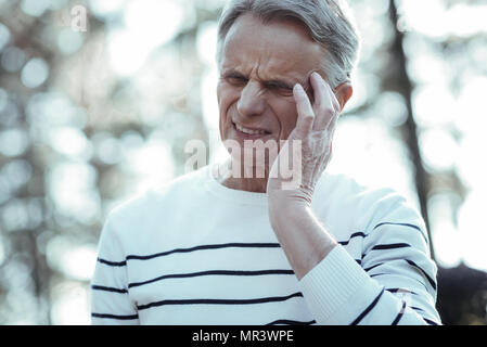 Elderly man making face from pain Stock Photo