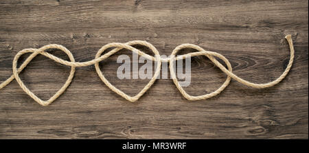 Three heart rope shapes on old wood Stock Photo