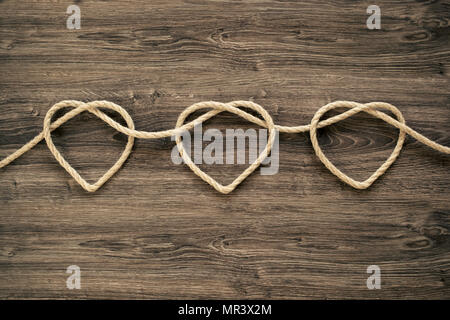 Three heart rope shapes  on old wood Stock Photo