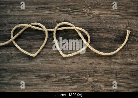 Two vintage rope heart shapes on old wood Stock Photo
