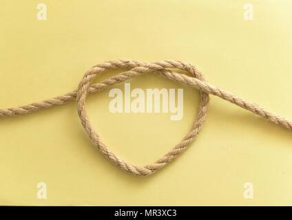 Heart shape made of rope on yellow background Stock Photo