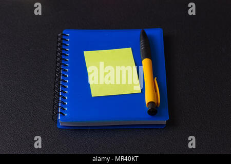 Blue notepad with multi-colored stickers and pen on a black background Stock Photo