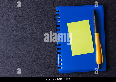 Blue notepad with multi-colored stickers and pen on a black background Stock Photo