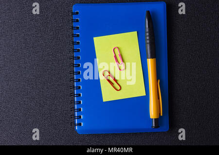 Blue notepad with multi-colored stickers and pen on a black background Stock Photo