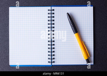 Open notepad on a spiral and pen on a black background Stock Photo
