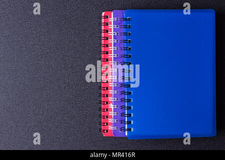 Several multi-colored notebooks on a spiral on a black background Stock Photo