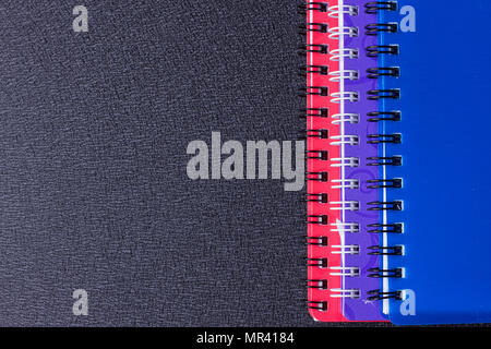 Several multi-colored notebooks on a spiral on a black background Stock Photo